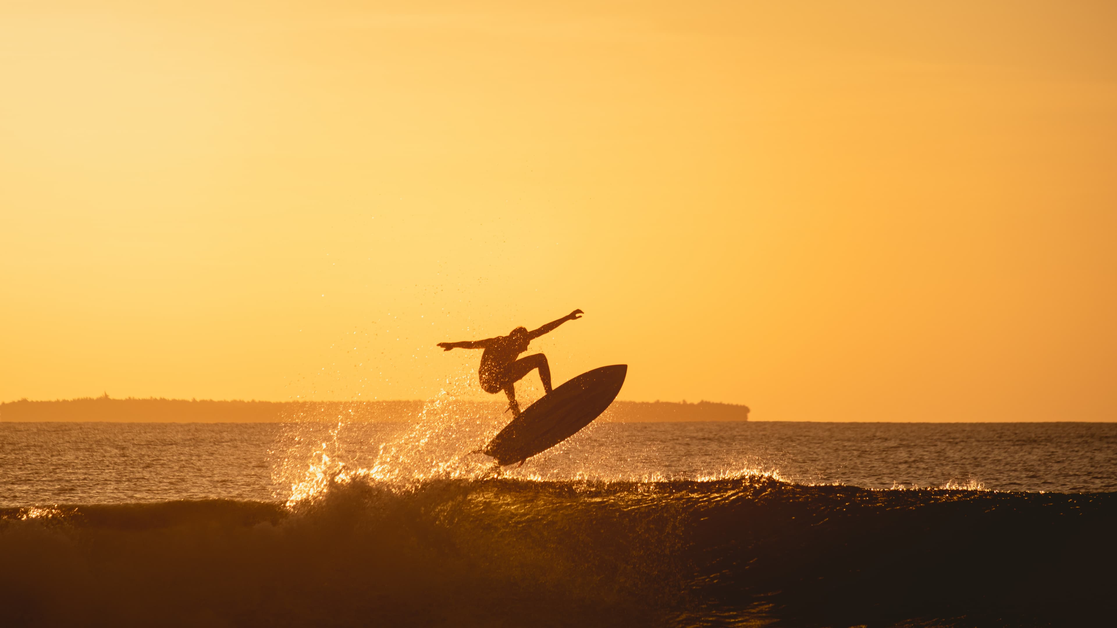 Surfista fazendo manobra no pôr do sol